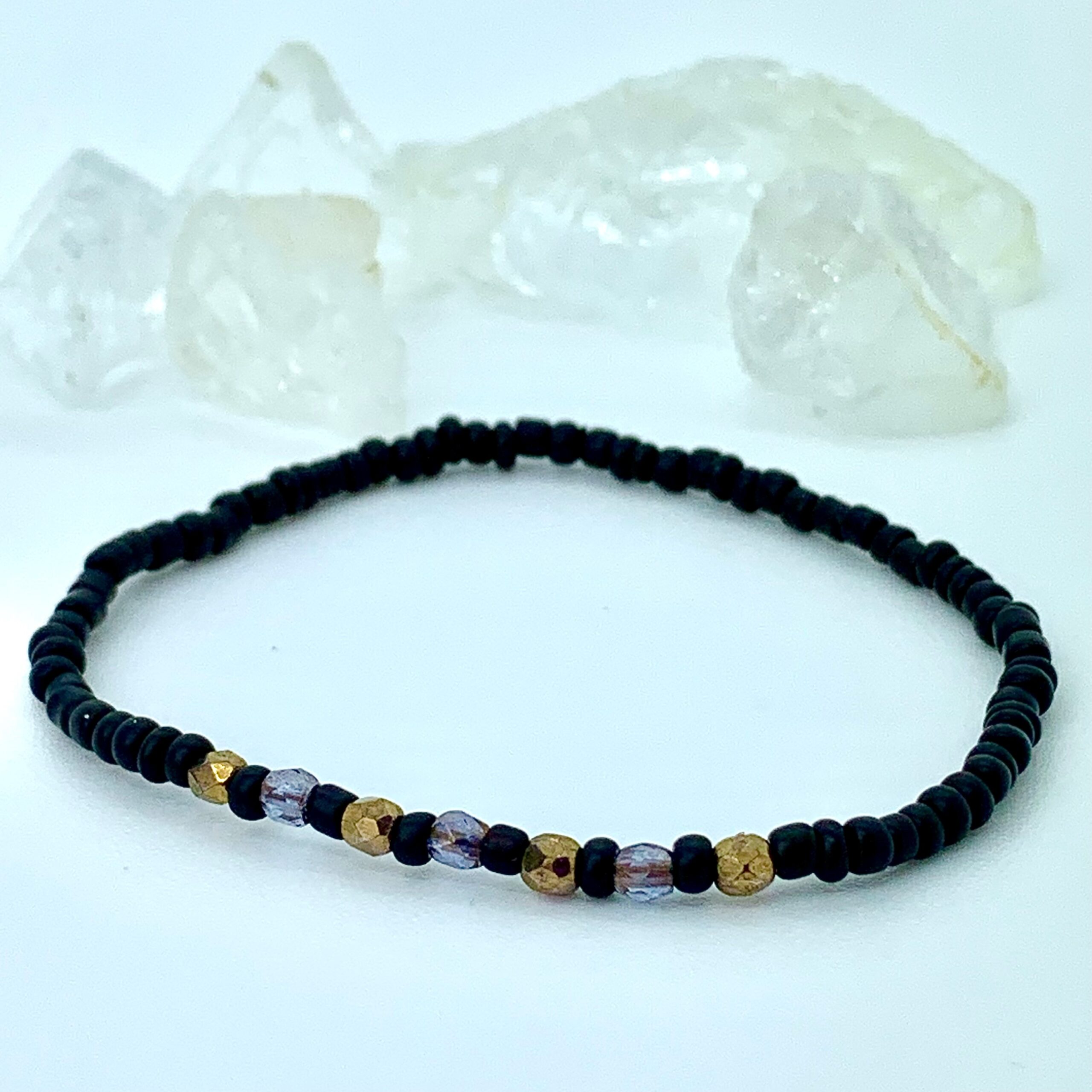 Hovedløse menneskemængde Slagter Armbånd af sorte matte perler og facetterede guld og lilla krystaller ·  Homemade By